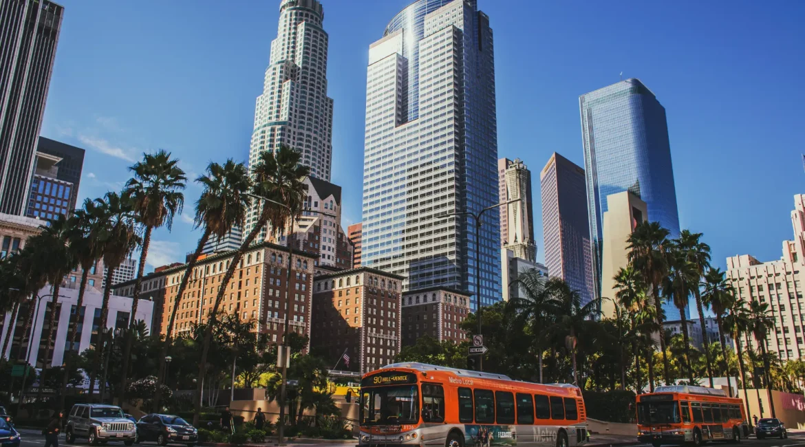 A city street featuring a bus and tall buildings under a clear sky.