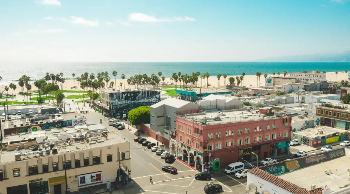 Aerial perspective of a city with buildings adjacent to a beach, highlighting urban and coastal features.